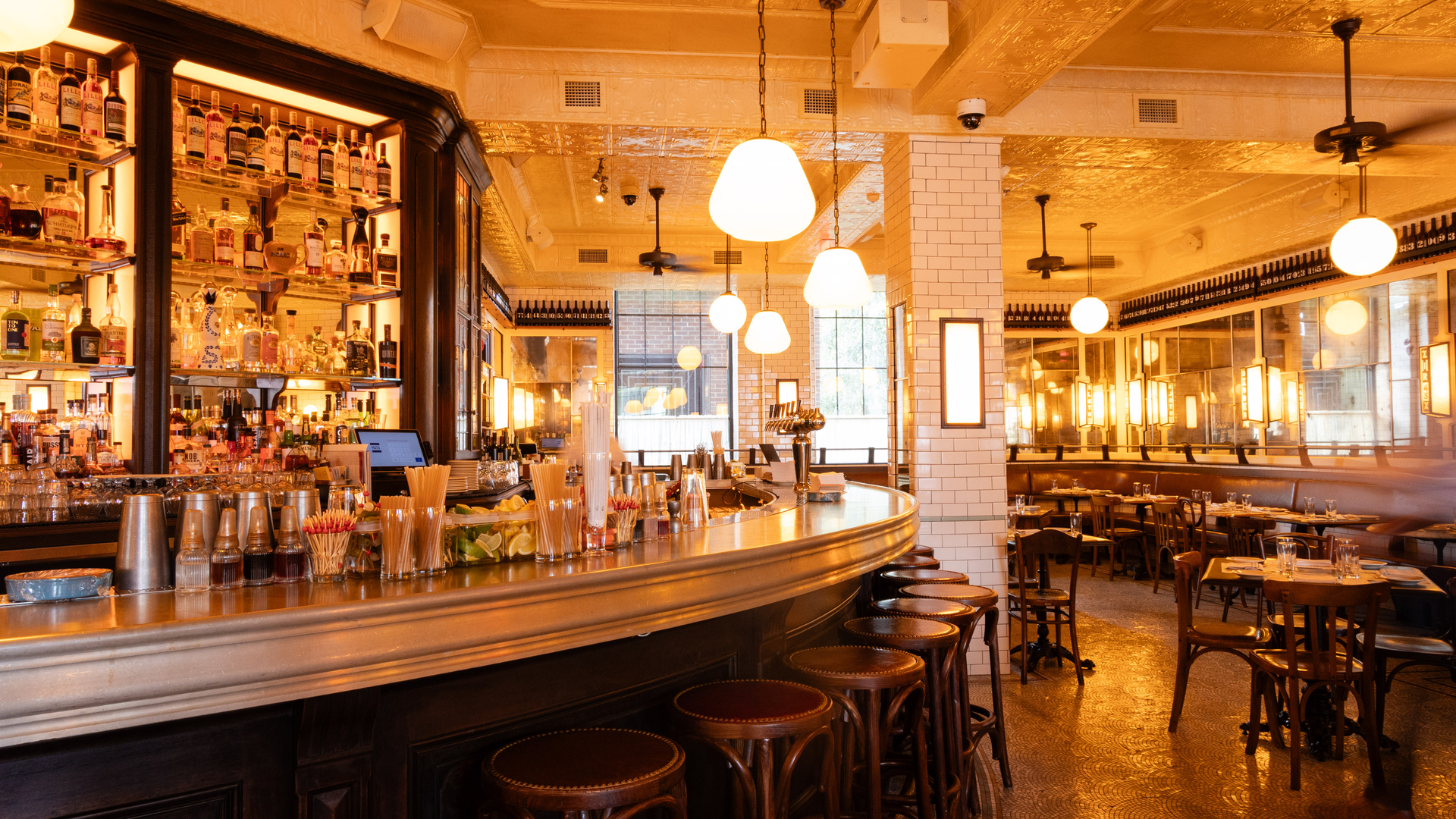 Vintage-style bar with wooden stools, glass shelves, and hanging lights in a warm-toned diner.